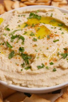 a white bowl filled with hummus next to crackers