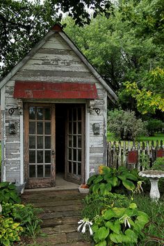 an old outhouse is surrounded by greenery and trees