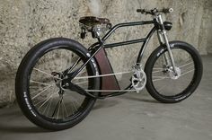 a black bike parked next to a stone wall with a basket on the front wheel