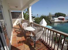 a balcony with chairs and tables overlooking the water