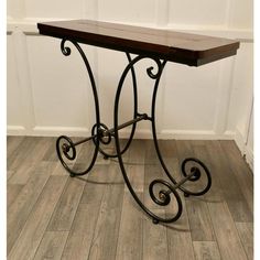 a wooden table sitting on top of a hard wood floor next to a white wall