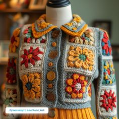 a crocheted jacket with colorful flowers on the shoulders and buttons at the collar