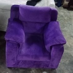 a purple chair sitting on top of a floor next to a bed