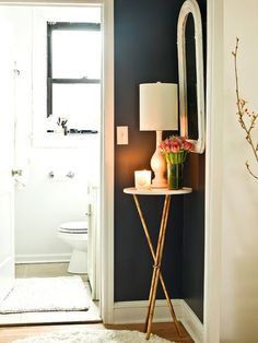 a small table with flowers on it in front of a door and a mirror behind it