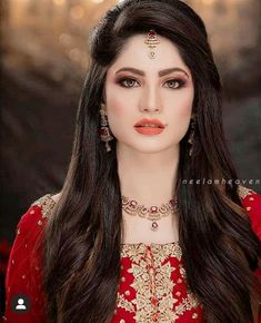 a woman with long dark hair wearing a red dress and gold jewelry on her head