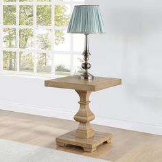 a wooden table with a lamp on it in front of a window and carpeted floor