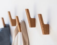 three pieces of wood hang on the wall next to each other, and one piece of fabric is tied up