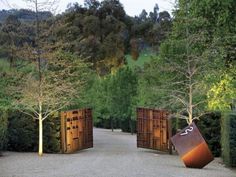 an outdoor area with trees, bushes and large sculptures in the shape of rectangles