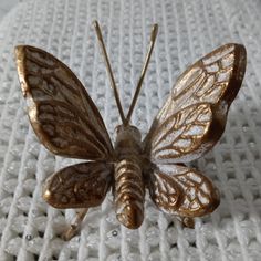 a golden butterfly sitting on top of a white blanket