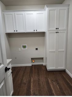 an empty room with white cabinets and wood floors