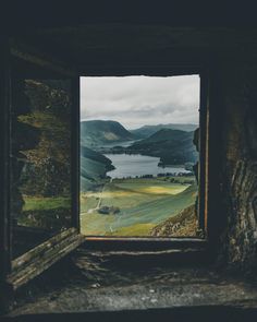 an open window with a view of mountains and water in the distance on a cloudy day