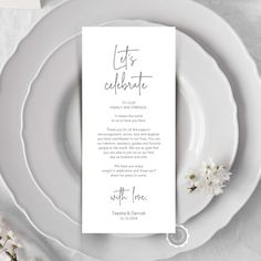 a place setting with white plates and flowers on the table, including a menu card