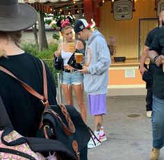 several people are standing outside with luggage and hats on their heads as they talk to each other