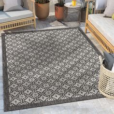 an outdoor area rug is shown on the patio with two couches and potted plants