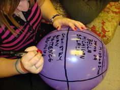 a woman is sitting on the floor with a large purple ball in her hands and writing on it