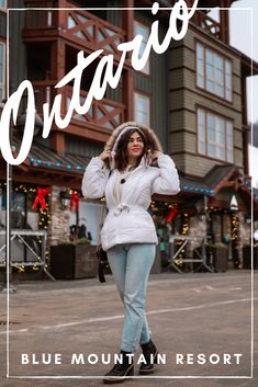 a woman is walking down the street wearing a white jacket and blue jeans with her hand on her head