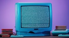 an old blue tv sitting on top of a wooden table next to a keyboard and mouse