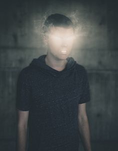 a young man standing in front of a wall with a light coming from his head