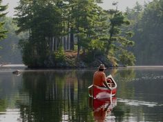 a man in a red canoe paddling on the water