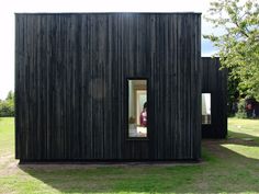 a black building with two people in the doorway and one person looking out from inside