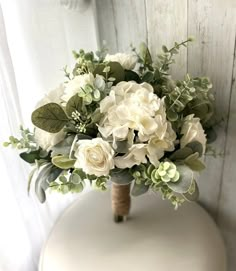 a bouquet of white flowers sitting on top of a table next to a window sill