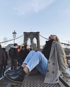 a woman sitting on the edge of a bridge with her feet up in the air