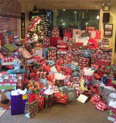 a pile of wrapped presents sitting in front of a christmas tree