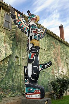 a totema statue stands in front of a building with a mural on it