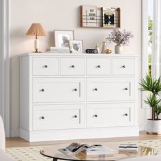 a white dresser in a living room with pictures on the wall above it and a coffee table