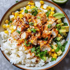 a bowl filled with rice, corn and chicken on top of a table next to a slice of lime