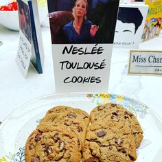 two chocolate chip cookies sitting on top of a plate next to a sign that says nestle tollones cookies