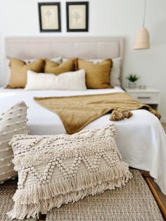 a bed with pillows and blankets on top of it next to two framed pictures above the bed