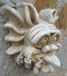 a close up of a face on a stone wall