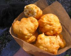 a person holding a paper bag filled with fried food on top of it's side