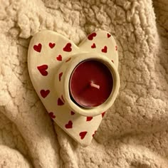 a heart shaped tea light holder with a candle in it sitting on a white blanket