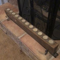 a wooden candle holder sitting next to a fire place