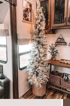 a white christmas tree in a brown basket next to a shelf with pictures on it