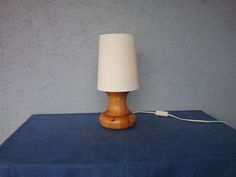 a wooden table with a white lamp on it and a blue cloth under the shade