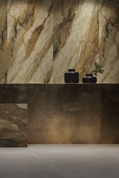 two black vases sitting on top of a counter next to a wall covered in marble