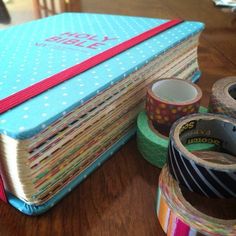 several rolls of tape sitting on top of a wooden table next to a blue book