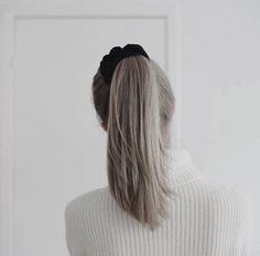 a woman with grey hair wearing a white sweater and black bow in front of a door