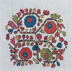 an embroidered design with red, blue and green flowers in the center on a white background