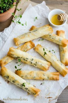 breadsticks with herbs and honey sit on wax paper next to a potted plant