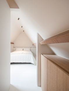 an attic bedroom with white walls and wooden furniture