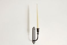 a candle that is on the wall next to a hook with a knife in it