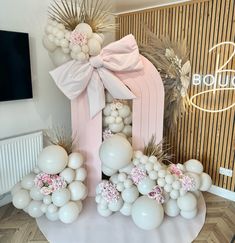 balloons and flowers are arranged in the shape of an arch with a bow on top