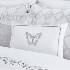 a close up of a pillow on a bed with a butterfly embroidered on the pillow