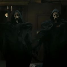 two people dressed in black robes and masks with their mouths open, standing next to each other