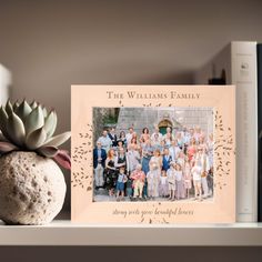 a family picture frame sitting on top of a shelf next to a potted plant