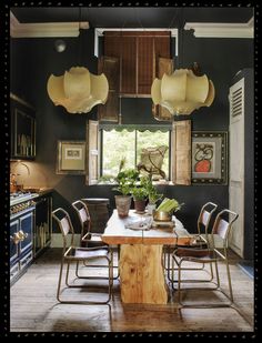 a dining room table surrounded by chairs and potted plants in front of a window